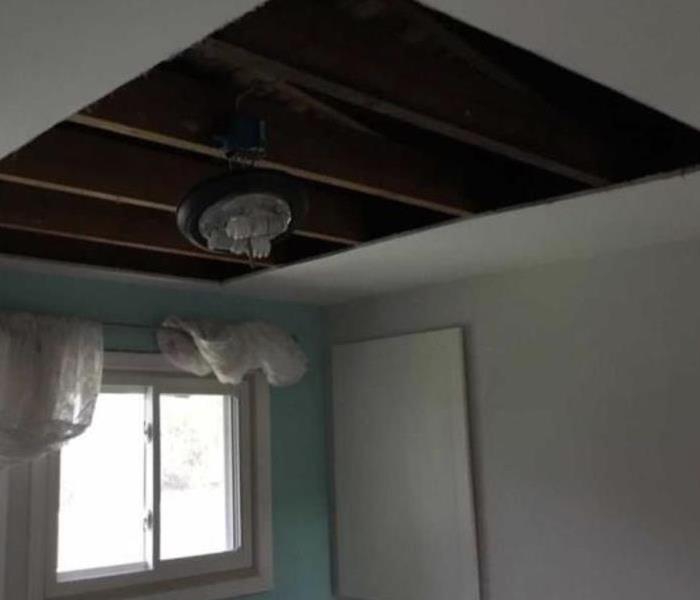 Bedroom damage from a pipe burst. The ceiling is cut out.