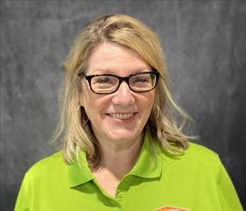 Female employee standing in front of grey backdrop wearing a lime green SERVPRO shirt