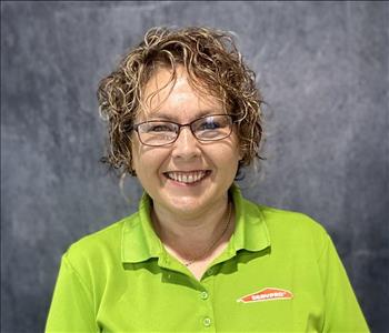 Female employee standing in front of grey backdrop wearing a lime green SERVPRO shirt