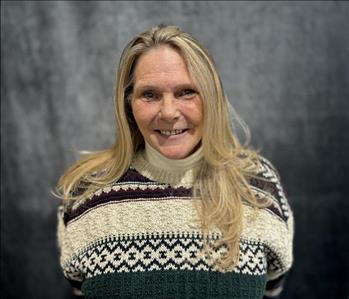 Female employee wearing a sweater standing in front of grey backdrop